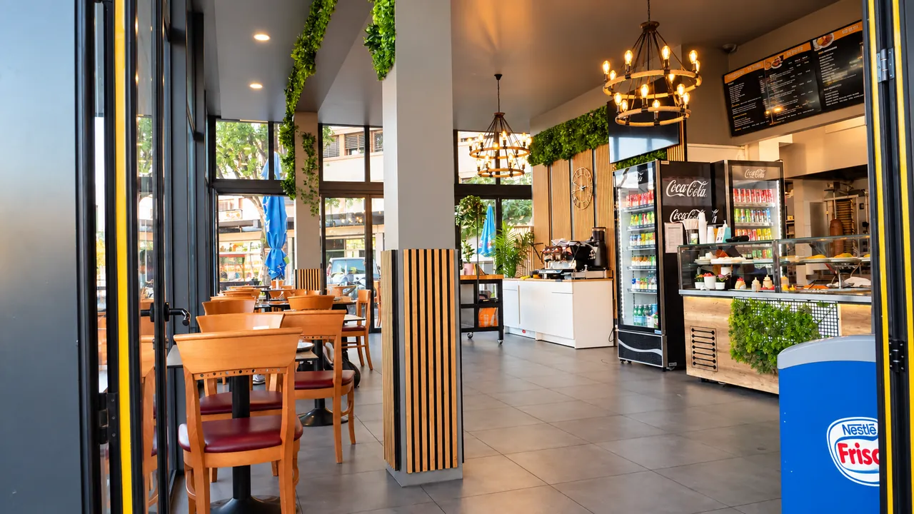 Intérieur de Tamaris Food : tables et chaises en bois, comptoir et vitrine réfrigérée